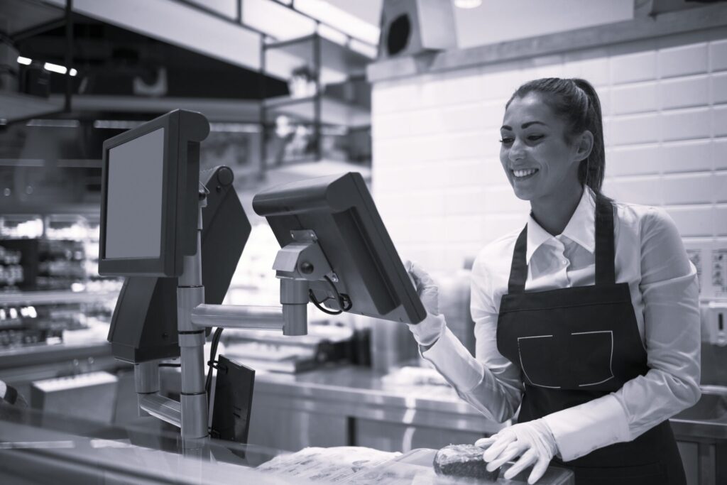 Supermarket worker measuring and selling meat to the customer.